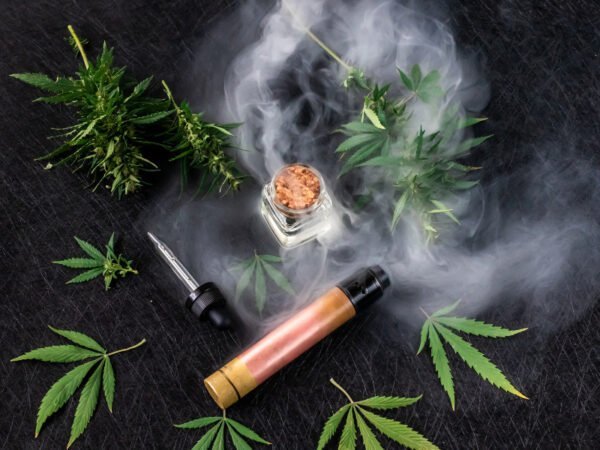 Cannabisblätter mit Extrakt, Feuer und einem Joint