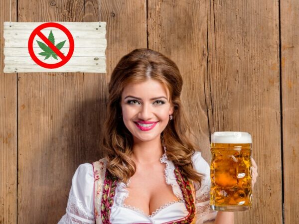 Eine Frau hält einen Maßkrug mit Bier, im Hintergrund ist ein Cannabis verboten Schild.