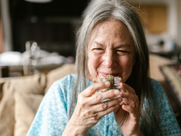 Cannabis bei älteren Menschen nutzen. Eine ältere Dame riecht an Cannabisblüten