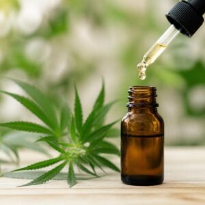 Wie wirkt CBD: CBD-Öl-Fläschchen mit Pipette neben Hanfblättern